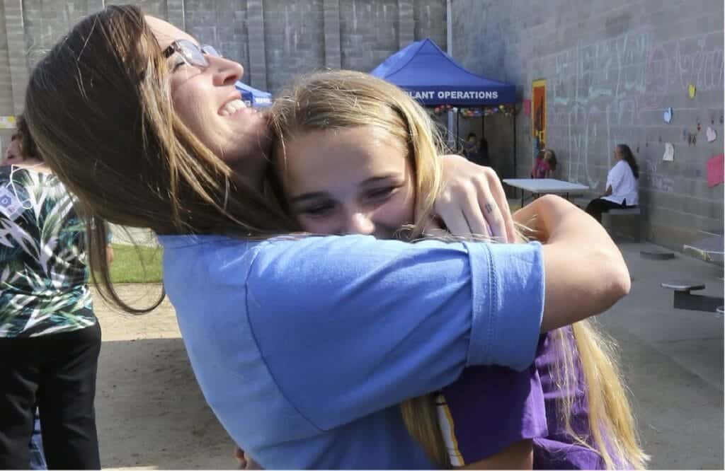 Young girl hugging an adult woman, symbolizing support and care for youth justice issues.